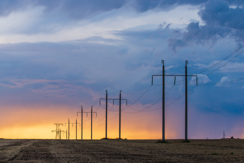 Rural landscape with high-voltage line on sunset. Dramatic sky view