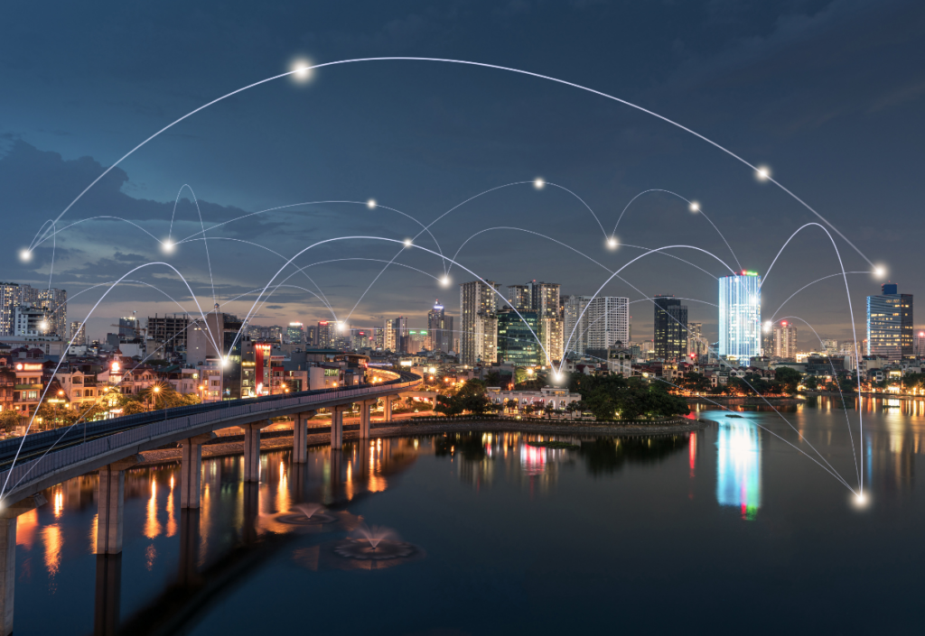 Cityscape at night with the buildings lit up. A graphic is overlaid showing the connected city.