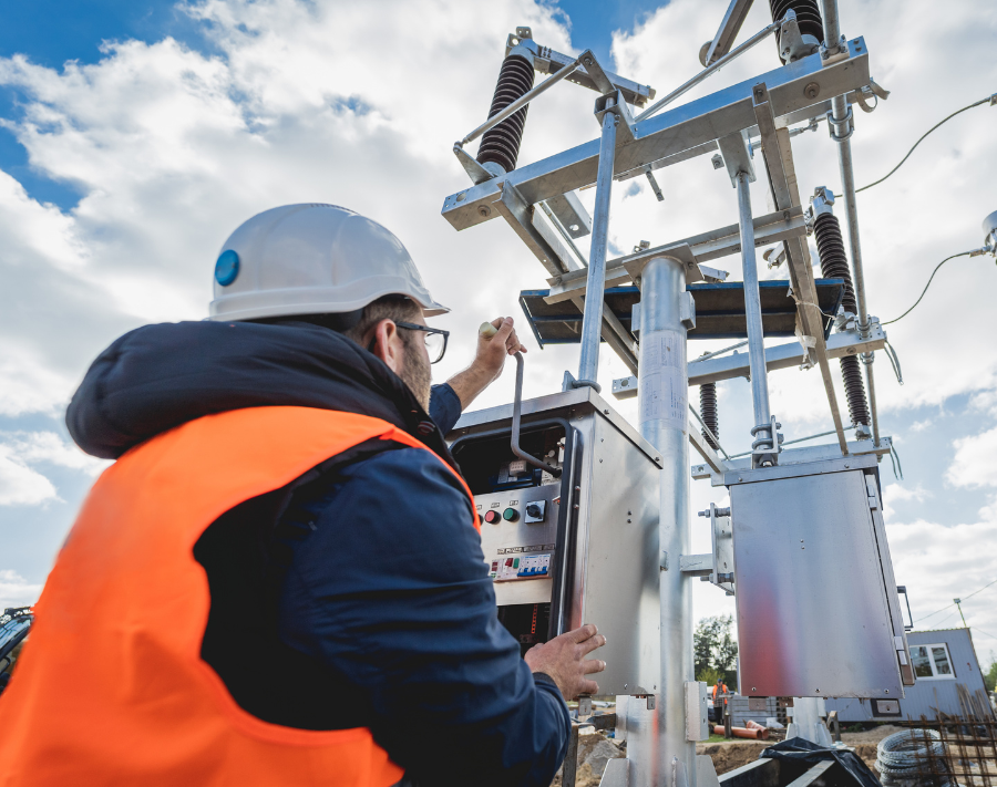 Worker in protective equipment working in an electrical box outside of a substation.