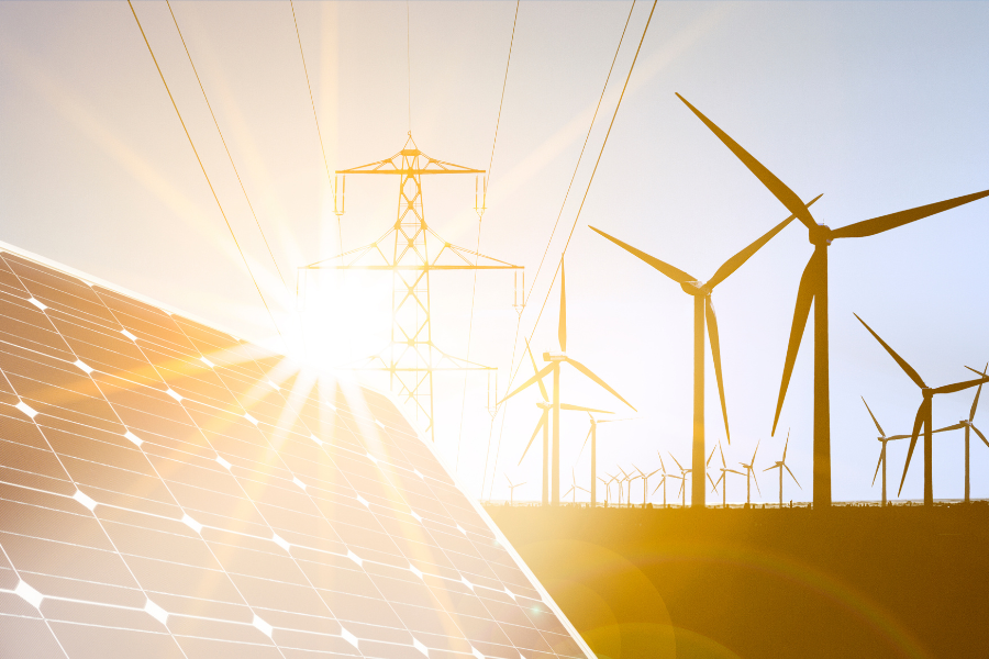 Solar panel in foreground with electrical transmission line and wind turbines in the background.